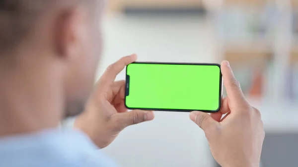 Afrikaner beobachtet Smartphone mit grünem Chroma-Schlüsselbildschirm — Stockfoto