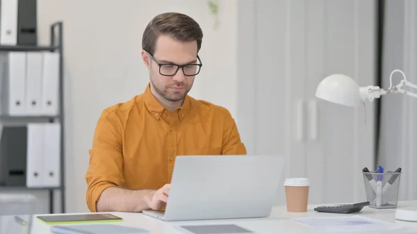 Jeune homme travaillant sur ordinateur portable au bureau — Photo