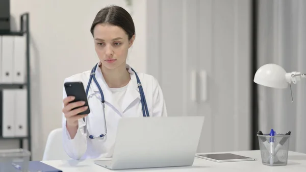 Vrouwelijke arts met laptop met behulp van Smartphone — Stockfoto