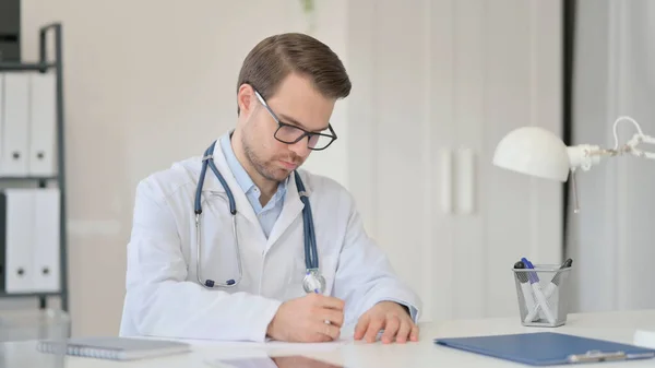 Mężczyzna lekarz pisanie na papierze w biurze — Zdjęcie stockowe