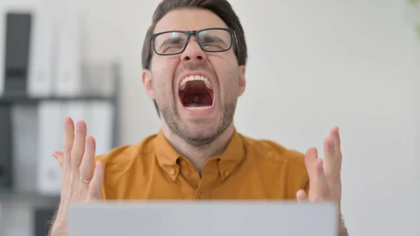 Primo piano del giovane con il computer portatile che grida in ufficio, fallimento — Foto Stock