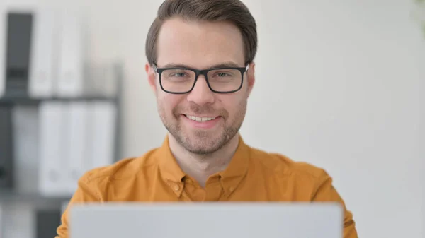Detailní záběr mladého muže s laptopem usmívajícího se na fotoaparát — Stock fotografie