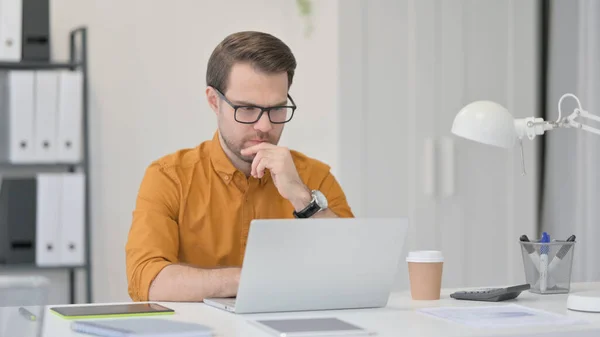 Hombre joven con ordenador portátil, Pensando en la oficina — Foto de Stock