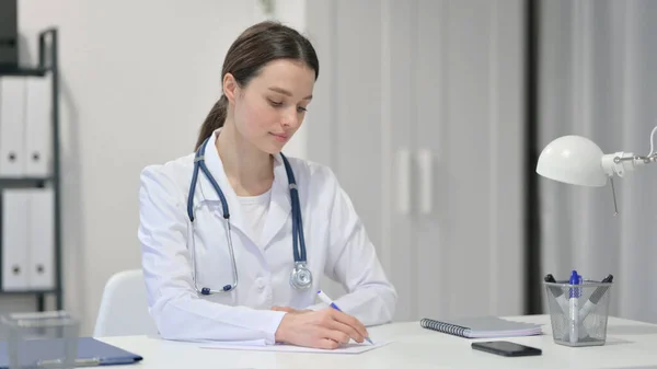 Vrouwelijke arts die op papier schrijft, medisch rapport — Stockfoto