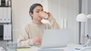 Laptoplu genç Hintli kadın kahve içiyor. 