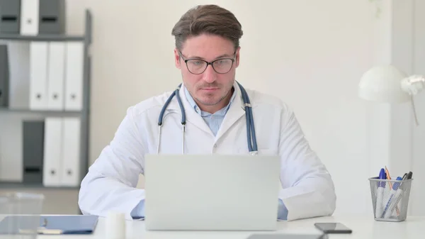 Середнього віку чоловік лікар працює на ноутбуці — стокове фото