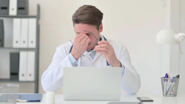 Κουρασμένος μεσήλικας γιατρός με φορητό υπολογιστή που έχει πονοκέφαλο — Φωτογραφία Αρχείου