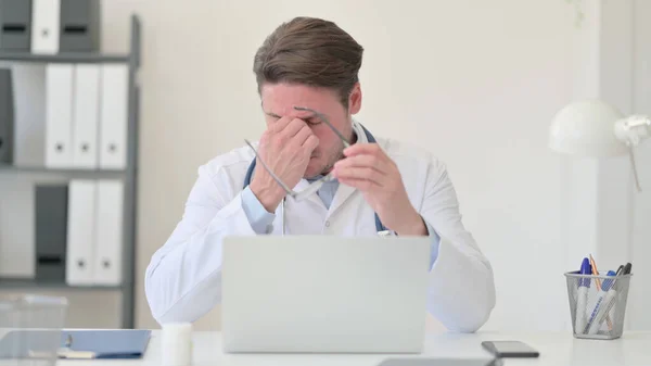 Lelah Middle Aged Male Doctor dengan Laptop memiliki sakit kepala — Stok Foto