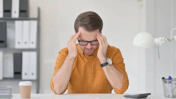 Unavený mladý muž s bolestí hlavy v kanceláři — Stock fotografie