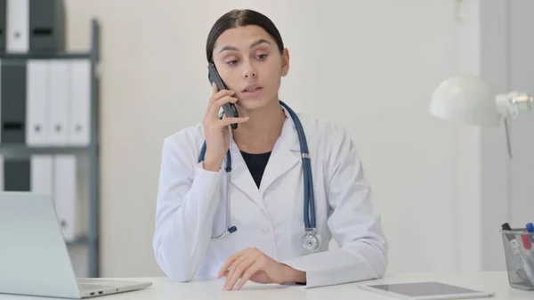 Vrouwelijke arts praten over de telefoon in de kliniek — Stockfoto