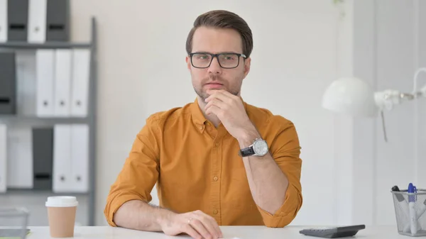 Pensando en un joven sentado en la oficina — Foto de Stock