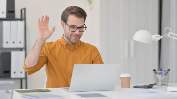 Appel vidéo sur ordinateur portable par le jeune homme au bureau — Photo