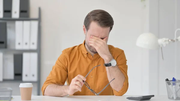 Yorgun genç adam baş ağrısı ve göz yorgunluğu çekiyor.