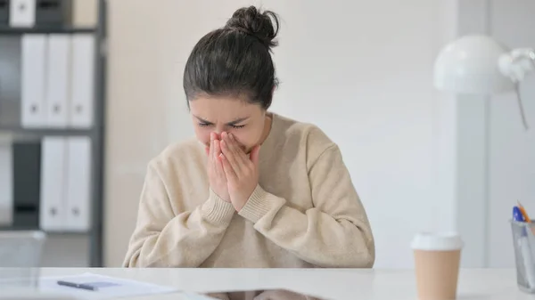 Young Indian Woman Sneezing in Office