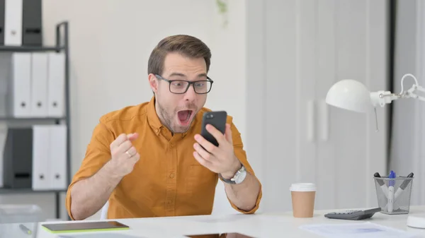 Spannende man viert succes op smartphone — Stockfoto