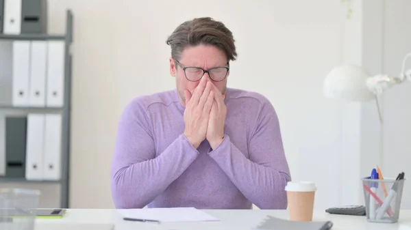 Middle Aged Man Sneezing in Office