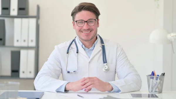 Médico masculino de mediana edad sonriendo a la cámara — Foto de Stock