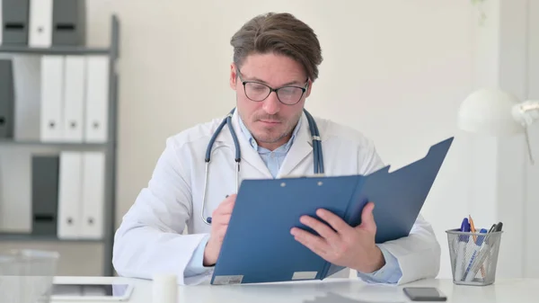 Médico masculino de mediana edad leyendo informe médico — Foto de Stock