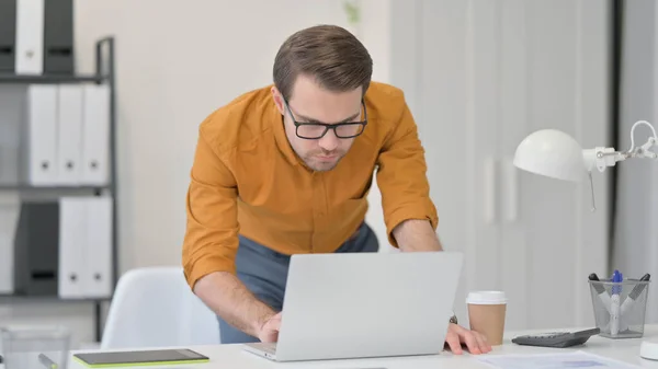 Jeune homme debout travaillant sur ordinateur portable au bureau — Photo