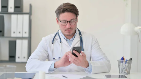 オフィスでスマートフォンを使用している中年男性医師 — ストック写真
