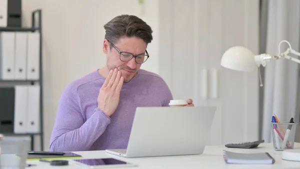 Hombre de mediana edad con portátil beber café con dolor de muelas — Foto de Stock