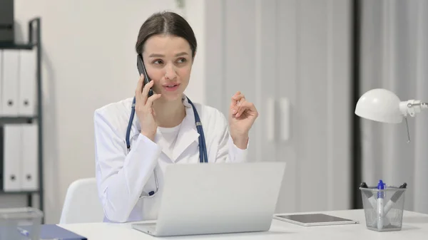 Vrouwelijke arts met laptop praten op Smartphone — Stockfoto