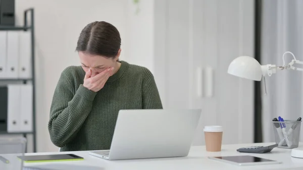 Young Woman with Laptop Sneezing in Office