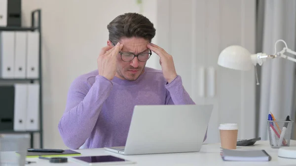 Чоловік середнього віку має головний біль в офісі — стокове фото