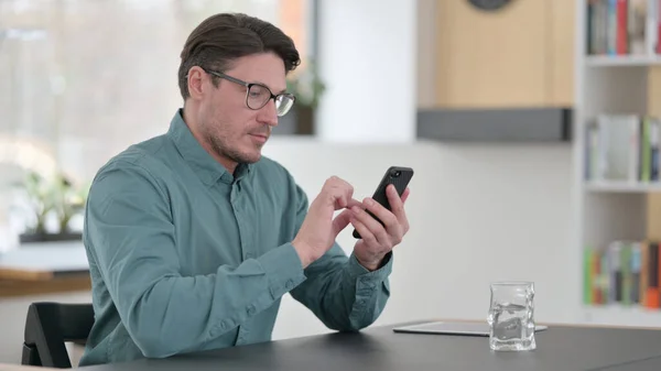Mellomaldermannen bruker Smartphone på arbeidsplassen – stockfoto