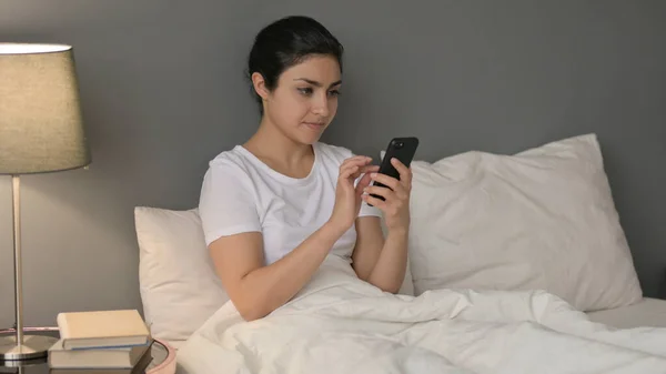 Уживання смартфонів молодою індійською жінкою в ліжку — стокове фото