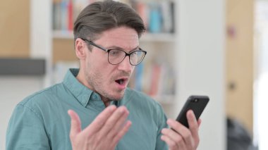 Orta yaşlı adam akıllı telefondan kayboluyor. 