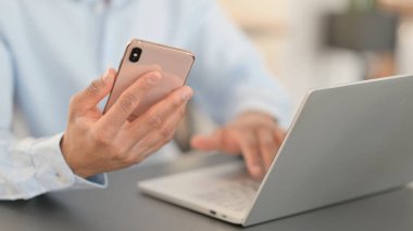 Akıllı telefon kullanan, dizüstü bilgisayarı olan Afrikalı adam, kapat 