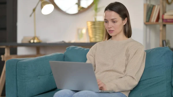 Schöne junge Frau mit Laptop auf Sofa — Stockfoto