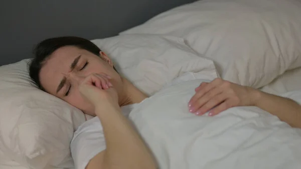 Fiatal nő köhögés feküdt az ágyban, influenza — Stock Fotó