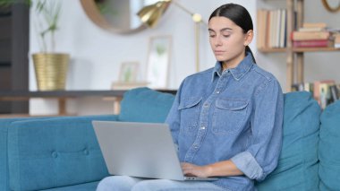 Kanepede dizüstü bilgisayar kullanan Latin Kadın 