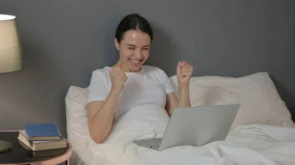 Atrakcyjna młoda kobieta świętuje na laptopie w łóżku — Zdjęcie stockowe