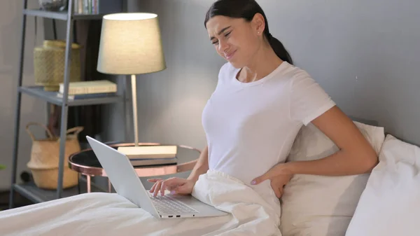 Latynoska kobieta z laptopem z bólem pleców w łóżku — Zdjęcie stockowe