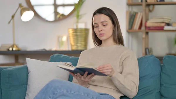 Junge Frau sitzt beim Lesen auf Sofa — Stockfoto