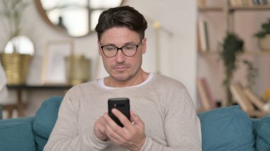 Evde akıllı telefon kullanan orta yaşlı bir adamın portresi