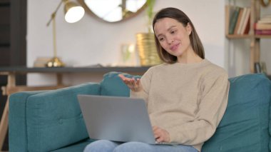 Dizüstü bilgisayardaki çevrimiçi görüntülü sohbet: Genç Kadın Kanepede 