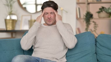 Stresli Orta yaşlı adam evde baş ağrısı çekiyor.