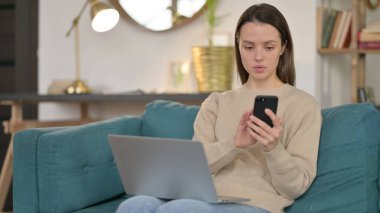 Genç kadın Smartphone ve Laptop üzerinde çalışıyor. 