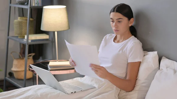 Latynoska kobieta z Laptop Czytanie dokumentów w łóżku — Zdjęcie stockowe
