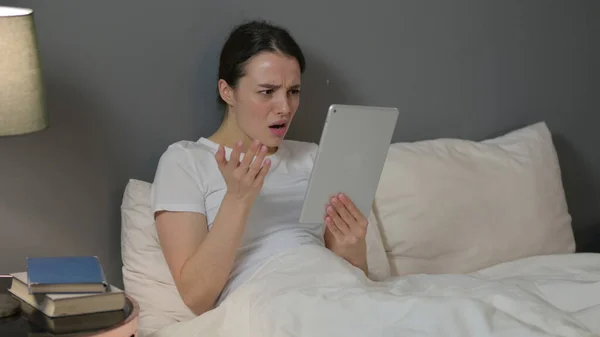 Молода жінка реагує на втрату планшета в ліжку — стокове фото