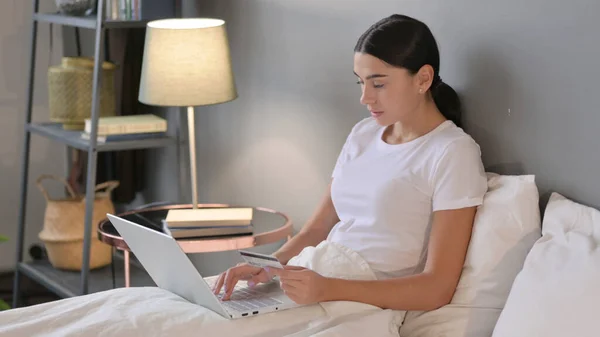 Płatności online na laptopie przez Latynoska kobieta w łóżku — Zdjęcie stockowe