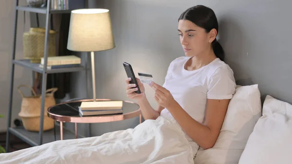 Erfolg beim Online-Bezahlen per Smartphone durch Latino-Frau im Bett — Stockfoto