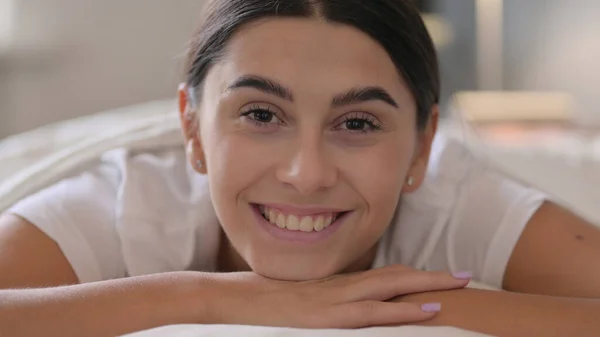 Retrato de una mujer latina acostada en la cama sonriendo ante la cámara —  Fotos de Stock