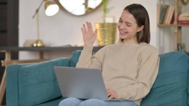 Dizüstü bilgisayardaki çevrimiçi görüntülü sohbet: Genç Kadın Kanepede 