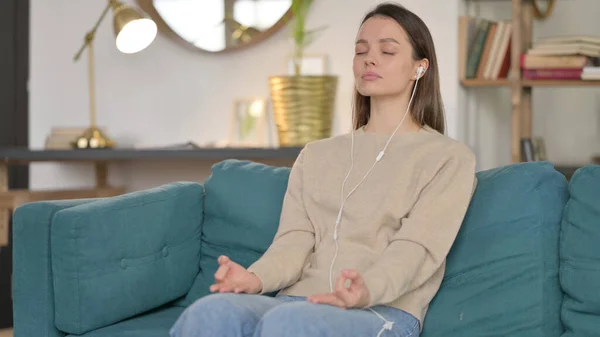 Молода жінка медитує, користуючись смартфоном на Софі — стокове фото