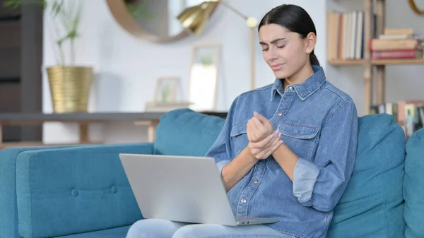 Femme latine avec ordinateur portable ayant la douleur au poignet sur le canapé — Photo